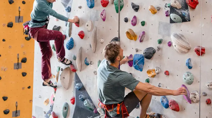 Zwei Personen bouldern nebeneinander an einer Boulderwand | © DAV/Marisa Koch